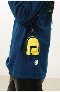 Detailed view of yellow mini backpack pouch with black hooks on a navy blue shirt