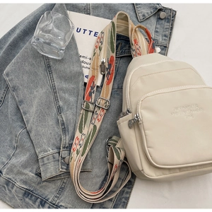 Detail of cream white mini backpack with modern age embroidery and colorful woven strap