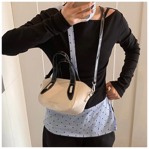Detail of a minimalist cream crossbody bucket bag with black trim and logo print