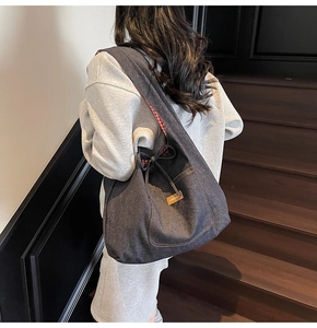 Detail of denim tote bag showing drawstring closure, bow, and red checkered lining