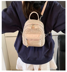 Rear view of model wearing a beige mini backpack with quilted heart pattern and PU leather