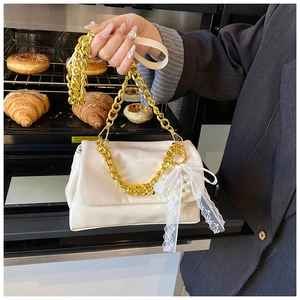 Close-up of white ruched cloud bag featuring gold chain and delicate pearl bow charms