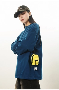 Close-up of bright yellow mini backpack pendant on blue long sleeve shirt with street style