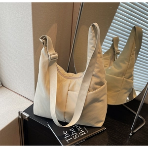 Detail of beige nylon crescent bag with adjustable strap and front zipper pocket