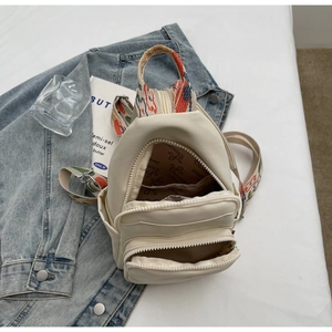 Detail of cream PU leather chest bag with ethnic embroidery strap and layered zippers