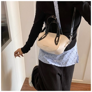 Detail shot of a cream leather crossbody bag with black handles and fashion lettering