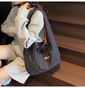 Detail of denim tote bag showing red gingham lining, drawstring bow, and exterior pocket