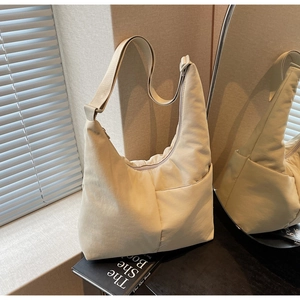 Detail of a beige nylon hobo bag featuring an adjustable strap and external pocket