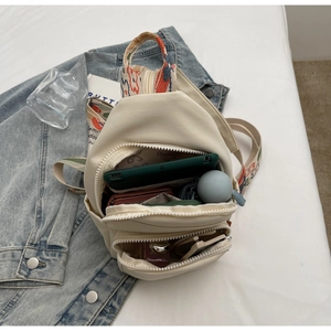 Detail view of cream multi-pocket crossbody bag showing internal storage for tablets and makeup