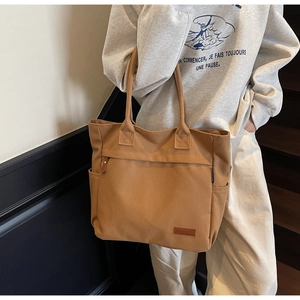 Detail view of large canvas tote bag showing side pocket and leather label on brown fabric