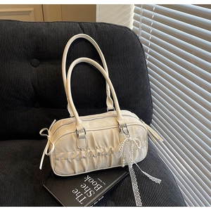 Close-up of pleated cream handbag with pearl lace bow detail on black corduroy sofa