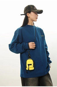 Stylishly compact yellow mini crossbody bag worn over a navy long sleeve sweatshirt