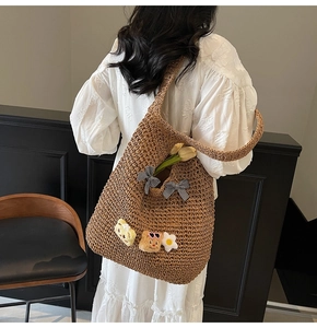 Détail du sac cabas en paille tissée avec nœuds à carreaux et breloques ours en peluche