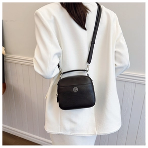 Vista posteriore di una modella in blazer bianco con borsa a tracolla nera minimalista