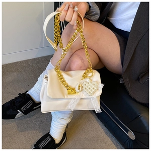 Detail of beige pleated leather handbag featuring gold chain strap and pearl heart charm