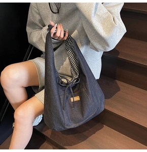 Detail of dark blue denim tote with brown leather tag and black gingham lining