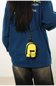 Rear view of a model wearing a mini yellow backpack pouch with a woven lanyard