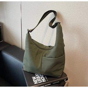 Detail of olive green quilted nylon shoulder bag with adjustable strap and side pocket