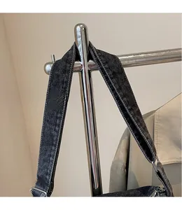 Detail of wide denim shoulder strap with white contrast stitching and metal ring buckle
