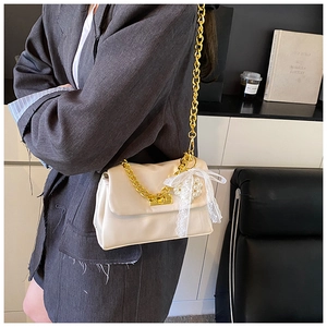Detail of off-white crossbody bag featuring gold chain strap and pearl lace bow accents