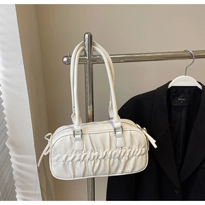 Detail of white pleated faux leather handbag with silver metal hardware on shoulder strap