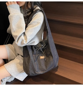Detail of denim tote bag showing exterior pocket, brand patch and checkered ribbon accent