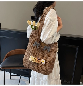 Détail du sac cabas en paille tressée avec broches de dessin animé et nœuds à carreaux