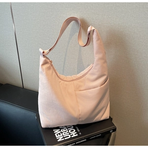 Close-up of light pink nylon crescent tote bag with front pocket and adjustable strap