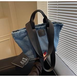 Détail d'un sac cabas en jean bleu clair avec des bretelles en nylon sur un fauteuil