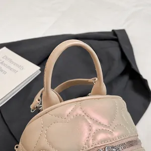 Détail d'un mini sac à dos matelassé or champagne avec poignée supérieure arrondie
