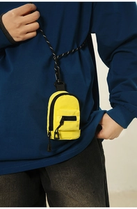 Close-up of a mini bright yellow nylon coin purse with a woven shoulder strap