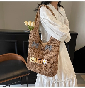 Détail d'un sac cabas en paille avec des nœuds noirs et des charms mignons sur l'épaule