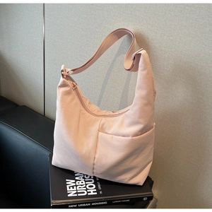 Detail of light pink nylon tote bag showing adjustable wide strap and zipper closure
