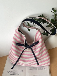 Pink and white striped canvas tote bag with navy bow detail in a stylish lifestyle setting