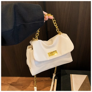 Detail of a creamy white pleated handbag with chunky gold chain handle and twist lock