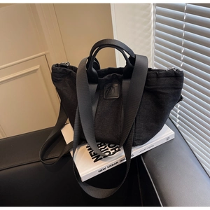 Gros plan d'un sac cabas en denim noir avec cordon de serrage sur canapé
