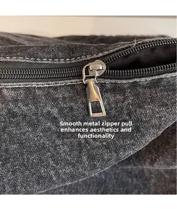 Close-up of smooth silver metal zipper puller on dark grey denim fabric texture