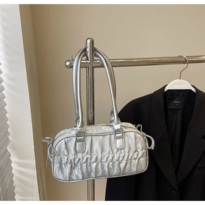 Detail of silver pleated bowling bag with side ribbon bow on metallic finish surface