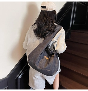 Detail of grey denim tote bag with drawstring closure and brown leather brand label