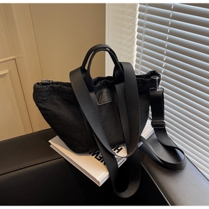 Détail macro du sac fourre-tout noir plissé avec logo D sur livres blancs et canapé