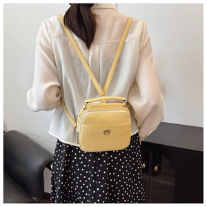 Vista posteriore di una modella con mini zaino in pelle giallo zenzero e fibbie metallo