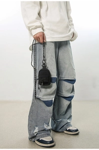 Detail shot of distressed light blue wide leg jeans with patchwork and raw hem finish