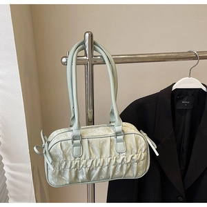Detail of mint green pleated hobo bag with side ribbon bow on a clothing rack