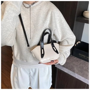 Detail of a contrast color crossbody bucket bag with black handles and fashion text
