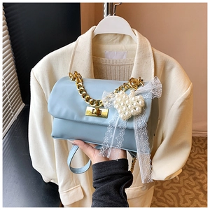 Detail of light blue crossbody bag with pearl heart charm and lace bow decoration