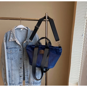 Détail du sac fourre-tout en denim bleu avec fermeture à cordon et large bandoulière noire