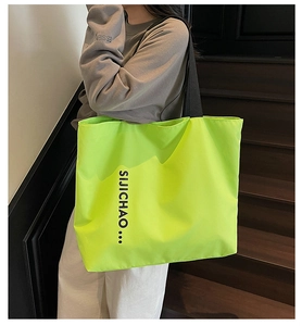 Detail showing high-capacity neon green tote bag with black letter print and shoulder strap