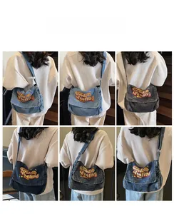 Detail view of denim messenger bags with Good Feeling embroidery and wide straps