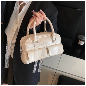 Detail of off-white Boston bag with delicate lace bow ornaments and flap pockets