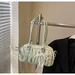 Detail of light green pleated shoulder bag with pearl bow charm and lace ribbons